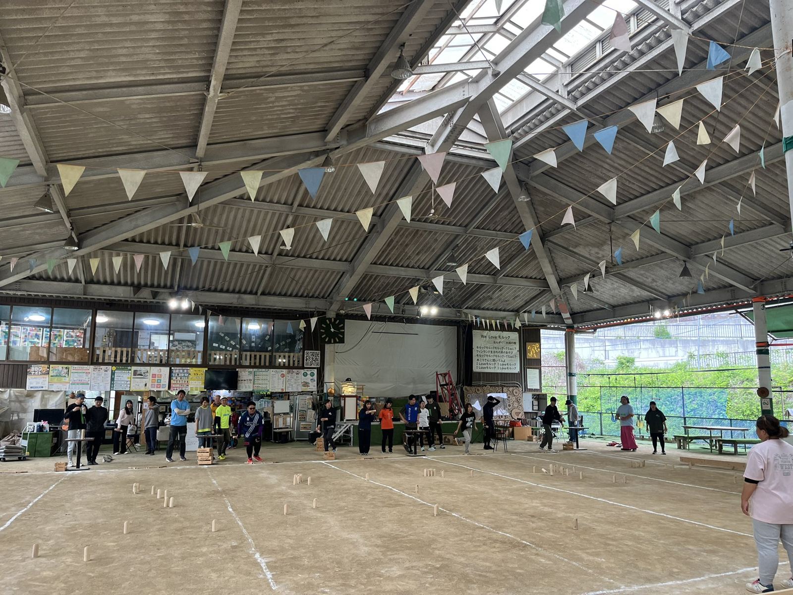 A large roofed Mölkky ground with bunting under the roof and several games in progress